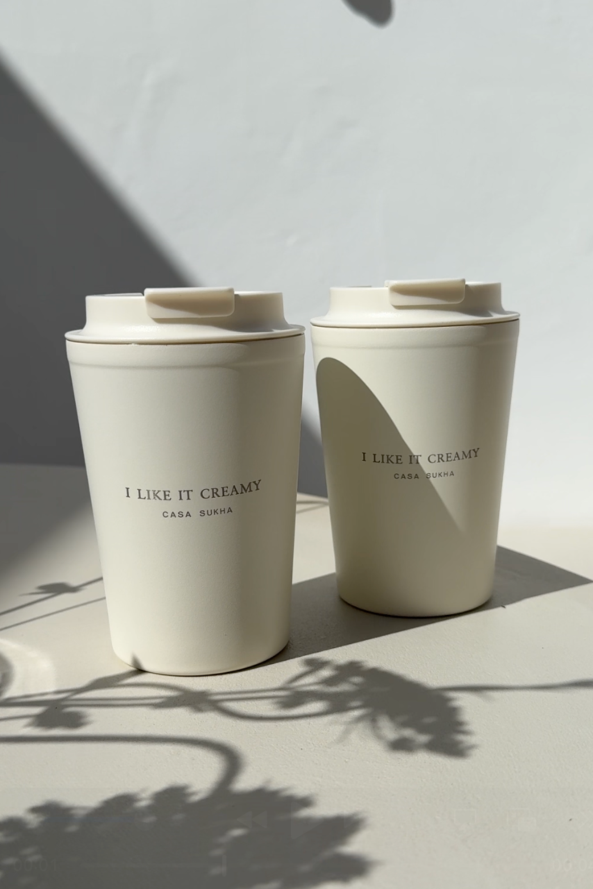 Close-up van de Casa Sukha 'I like it creamy' koffiemok. Beige to-go beker